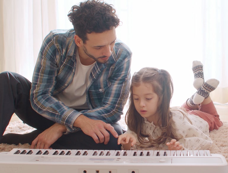 Daughter playing the EZ-310 and father watching on the floor