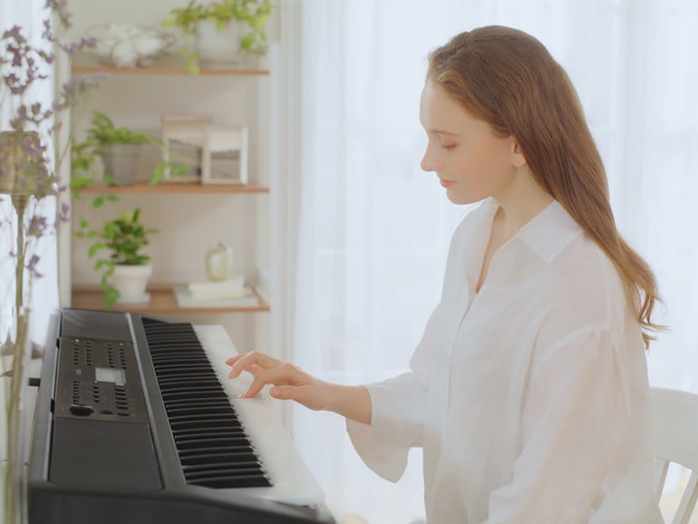 Woman playing the PSR-EW320 with one hand.