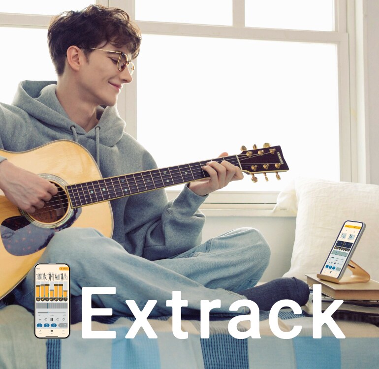 소파에 앉아 Extrack 음악 연습 앱에 맞춰 기타 연습을 즐기고 있는 남성